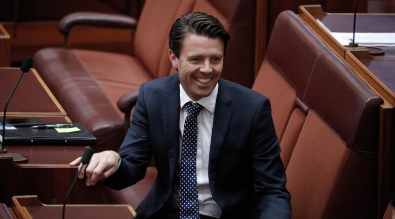 Duniam smiles, sitting on the senate benches.