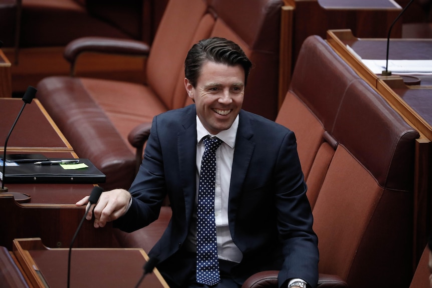 Duniam smiles, sitting on the senate benches.